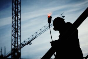 a man on a construction site holding a blowtorch