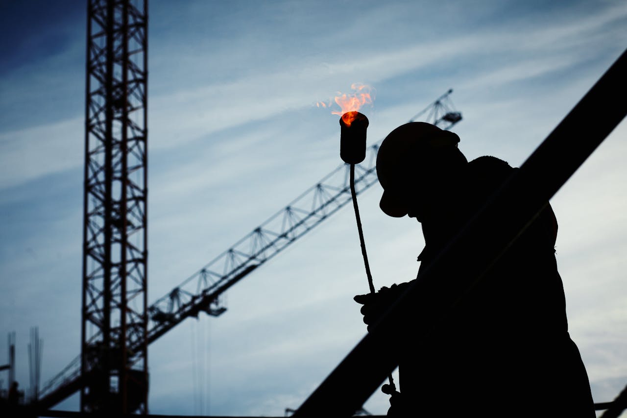 a man on a construction site holding a blowtorch
